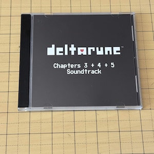 May include: A square CD jewel case with a black cover featuring the white pixelated text "deltarune" with a small red heart icon in the center, followed by the white text "Chapters 3 + 4 + 5 Soundtrack" centered below the title.