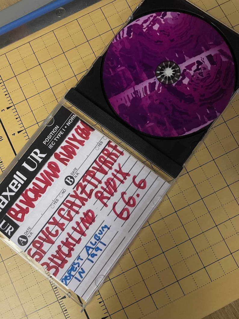 May include: A black CD case with a purple CD inside. The case has handwritten text on it, including "BLVCKLVND RUDIX", "SPVCX CAXZTPVRRF", "POPEST ALBUM", "IN 1991", and "66.6".