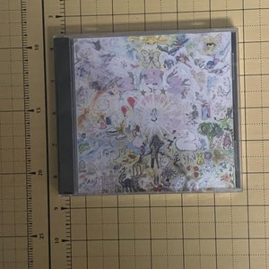 May include: A CD case with a colorful, abstract design featuring a variety of shapes, colors, and patterns. The design includes stars, butterflies, and other whimsical elements.