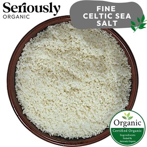May include: A close-up of a brown bowl filled with fine white Celtic sea salt. The salt is certified organic and packed by Seriously Organic.