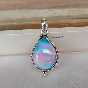 May include: A teardrop-shaped pendant with a silver setting and a colourful opal stone. The opal has a rainbow of colours, including pink, blue, and green.