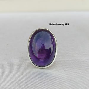 Könnte beinhalten: Ein silberner Ring mit einem großen ovalen Amethyst-Edelstein. Der Ring ist in einer schlichten Silberfassung gefasst.