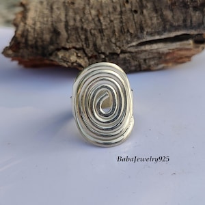 May include: A silver ring with a spiral design. The ring is oval shaped and has a smooth, polished finish.