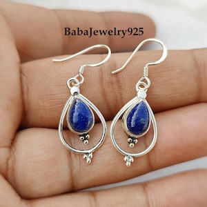 Puede incluir: Un par de pendientes de plata con una piedra de lapislázuli en forma de lágrima en cada pendiente. Los pendientes tienen un diseño delicado y calado y están adornados con pequeñas cuentas de plata.