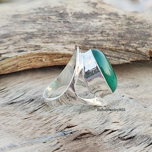 May include: A silver ring with a large, oval-shaped green gemstone set in a unique, open-work design.