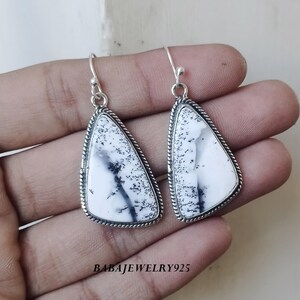 Peut inclure: Une paire de boucles d'oreilles pendantes en argent avec une pierre d'agate dendritique blanche et noire. Les pierres sont de forme triangulaire et ont une bordure en forme de corde.