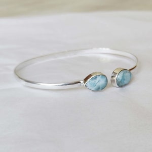 Op de afbeelding: Een zilveren armband met twee druppelvormige blauwe lace agaat stenen.