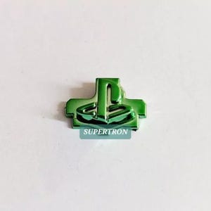 May include: A green PlayStation button featuring the PlayStation logo in a raised design. The button is made of plastic and has a glossy finish.