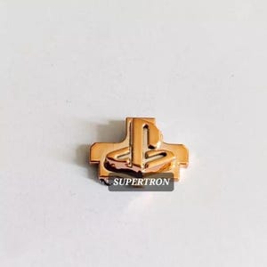 May include: A gold-coloured PlayStation button replacement with the PlayStation logo in the centre.