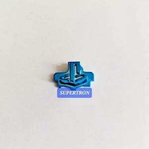 May include: A blue PlayStation button with a white PlayStation logo. The button is made of plastic and has a glossy finish.