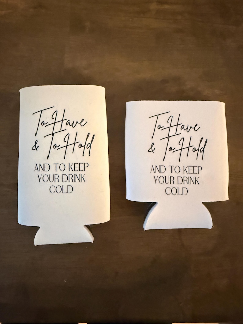 May include: Two white foam beverage insulators of different heights, each featuring black printed text that reads: To Have & To Hold AND TO KEEP YOUR DRINK COLD. The taller sleeve is designed for slim cans, while the shorter sleeve fits standard cans.