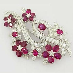 May include: A silver brooch with a floral design featuring red rubies and white diamonds. The brooch is shaped like a branch with several flowers and leaves.
