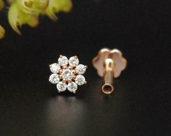 May include: A rose gold flower-shaped nose stud with a cluster of small clear diamonds.