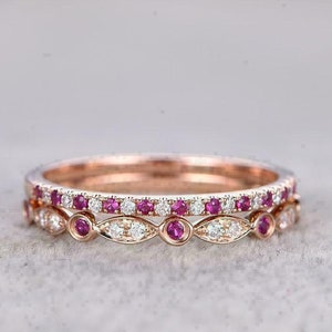 Può includere: Un set di due anelli delicati in oro con una fila di piccole pietre preziose rosa e una fila di piccole pietre preziose trasparenti.