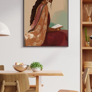 May include: Framed art print depicting a woman in traditional Indian dress, seated and reading. The artwork shows a woman in a maroon sari with a floral shawl. The woman has dark hair and wears gold earrings. The print is in a dining room setting.