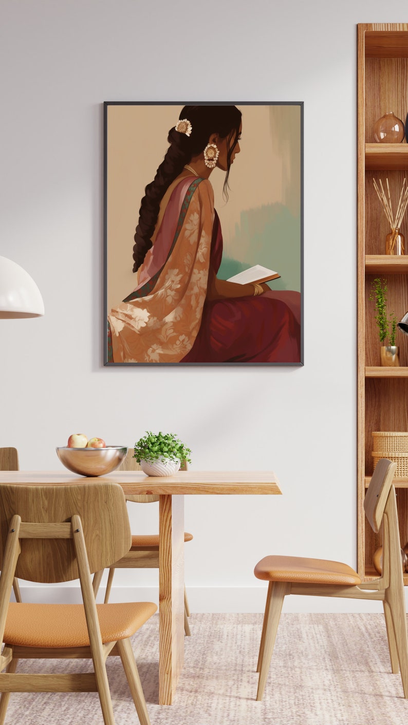 May include: Framed art print depicting a woman in traditional Indian dress, seated and reading. The artwork shows a woman in a maroon sari with a floral shawl. The woman has dark hair and wears gold earrings. The print is in a dining room setting.