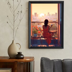 May include: A woman in a red dress sits on a balcony overlooking a city skyline at sunset. She is holding a cup and looking out at the view.