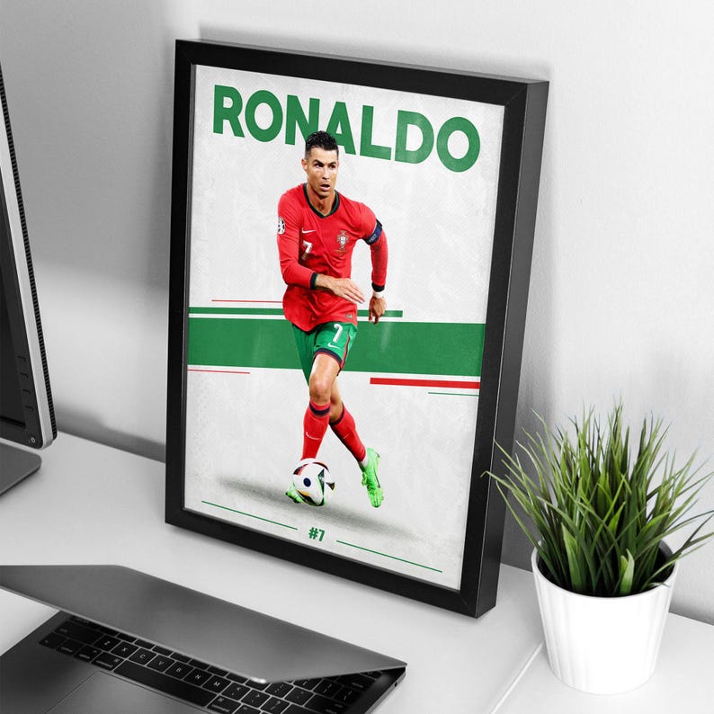 May include: Framed poster featuring Cristiano Ronaldo in a red soccer uniform with the number 7. The poster has a white background with green and red stripes. The word "RONALDO" is printed in large green letters at the top.