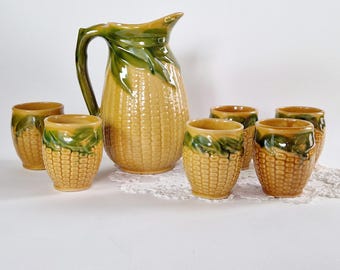 Zestaw do napojów z ceramiki w kształcie kukurydzy z sześcioma kubkami i dużą butelką w stylu retro. Ceramiczne szklanki do kukurydzy w stylu vintage. Żółte ceramiczne kubki w stylu vintage.