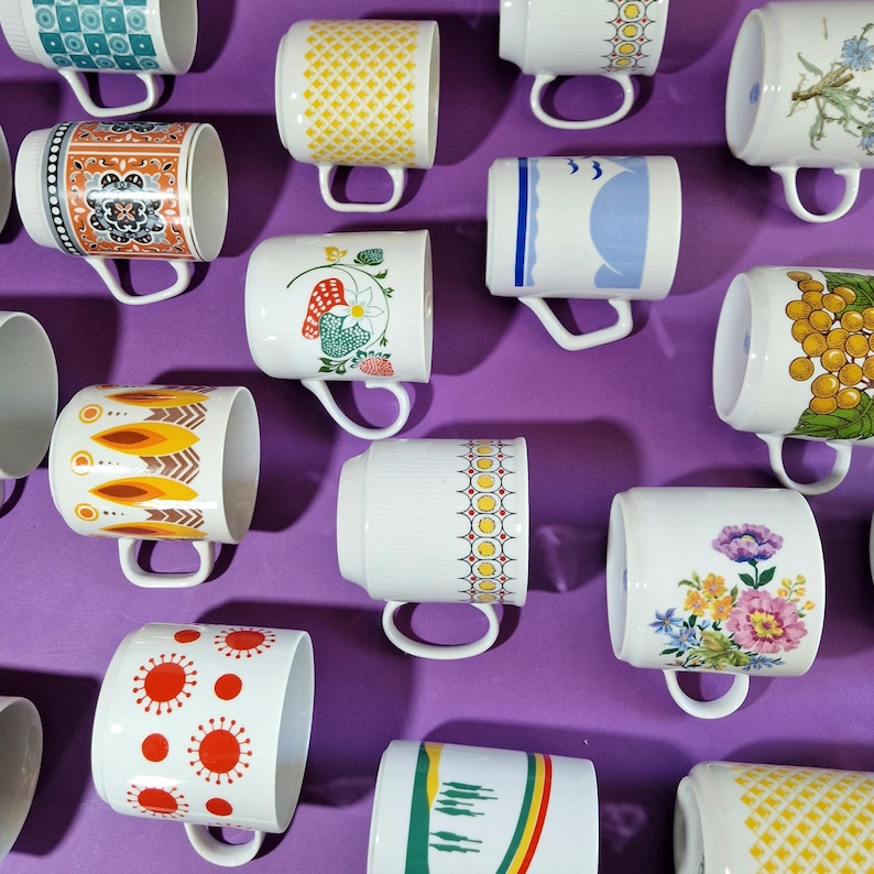 Może przedstawiać: Kolekcja ceramicznych kubk&oacute;w z r&oacute;żnymi wzorami i wzorami. Kubki mają motywy kwiatowe, geometryczne i abstrakcyjne w kolorach takich jak ż&oacute;łty, pomarańczowy, niebieski i czerwony. Każdy kubek ma biały uchwyt i jest umieszczony na fioletowym tle.