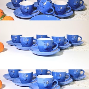 Op de afbeelding: Een set blauwe keramische kopjes en schotels. Elke kop heeft een lachend gezichtsontwerp met een witte binnenkant. De schotels zijn bijpassend blauw. Ideaal voor het serveren van thee of koffie.