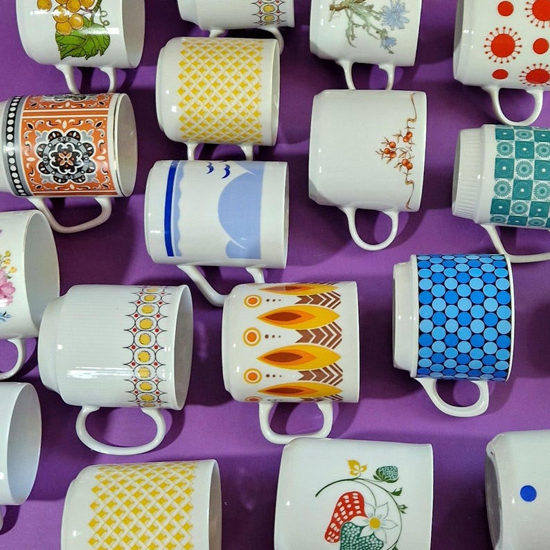 Może przedstawiać: Kolekcja ceramicznych kubk&oacute;w w stylu vintage z r&oacute;żnymi wzorami i kolorami. Kubki mają wzory takie jak kwiatowe, geometryczne i abstrakcyjne. Kubki są białe z kolorowymi akcentami i mają uchwyt.