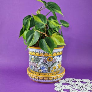Puede incluir: Una taza de cerámica blanca con un asa negra y el texto "But First, Coffee" en negrita negra. La taza está sobre un fondo borroso. La taza mide aproximadamente 10 cm de altura.