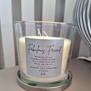 May include: A clear glass candle jar with a silver lid and a gray label that reads "Fabulous Friend" with the text "Because of you I laugh a little harder, cry a little less and smile alot more. ALWAYS AND FOREVER Friends XX".