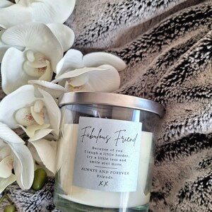 May include: A white candle in a clear glass jar with a silver lid. The label on the jar reads "Fabulous Friend" and includes the text "Because of you I laugh a little harder, cry a little less and smile a lot more. Always and Forever Friends XX".