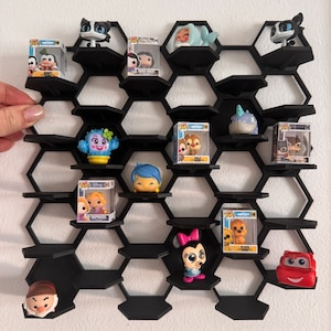 Peut inclure: Étagère hexagonale noire avec différentes figurines Funko Pop exposées sur les étagères. Les figurines comprennent des personnages comme Mickey Mouse, Raiponce et Minnie Mouse.