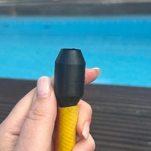Peut inclure: Une buse de tuyau en caoutchouc noir avec un tuyau jaune attaché. La buse est conçue pour se connecter à un tuyau d'arrosage.