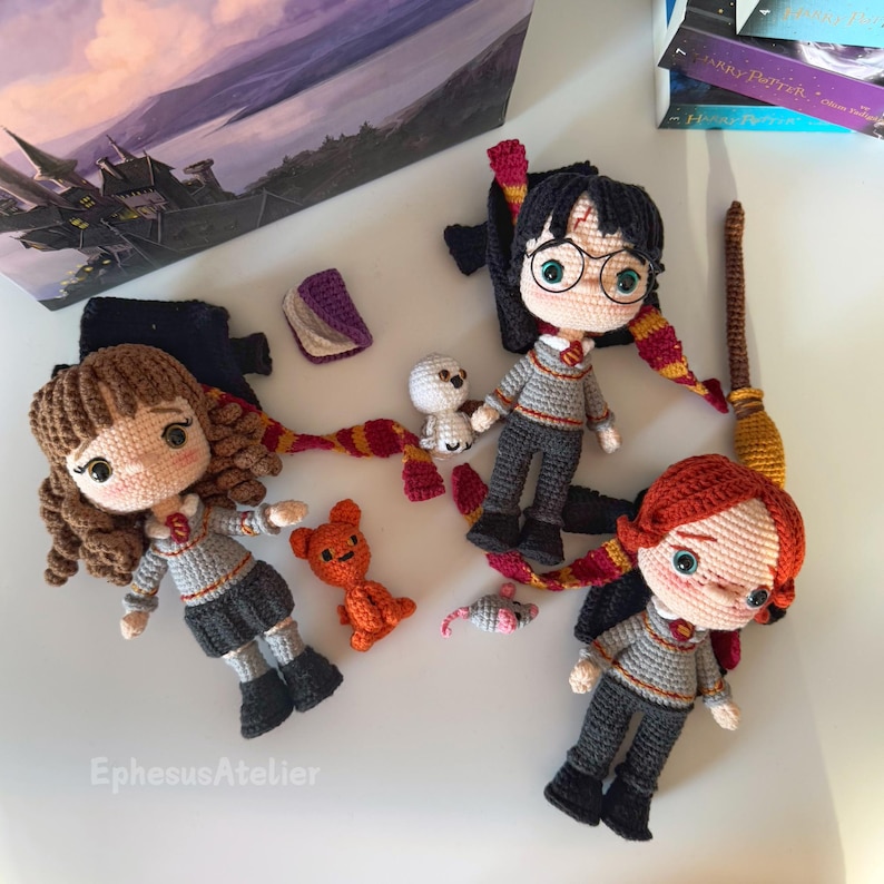 Pode incluir: Bonecas amigurumi de croch&ecirc; de Harry Potter, Hermione Granger e Rony Weasley. As bonecas est&atilde;o vestidas com seus uniformes escolares de Hogwarts e est&atilde;o segurando v&aacute;rios acess&oacute;rios, incluindo um livro, uma varinha m&aacute;gica e um animal de pel&uacute;cia.