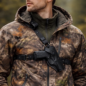 Könnte beinhalten: Ein schwarzes Brustholster aus Leder mit einer Handfeuerwaffe wird über einer Tarnjacke getragen. Die Jacke hat ein braunes, grünes und orangefarbenes Muster. Eine passende Camouflage-Baseballkappe wird getragen.