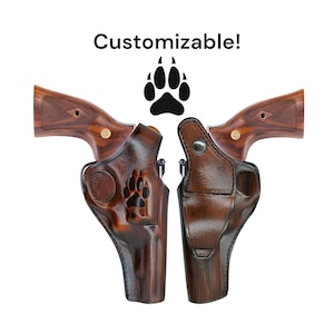 Könnte beinhalten: Zwei braune Lederholster für einen Revolver mit einem Pfotenabdruck-Design. Die Holster sind anpassbar. Der Text "Customizable!" befindet sich über den Holstern.