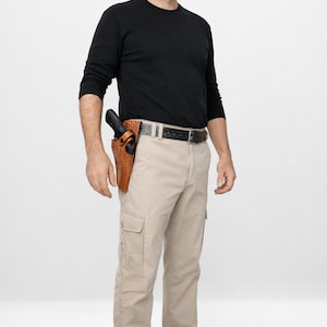 Può includere: Un uomo indossa una maglietta nera a maniche lunghe, pantaloni cargo color cachi e scarpe da ginnastica beige. Una fondina in pelle marrone con una pistola nera è attaccata alla sua cintura. La cintura è nera con una fibbia argentata.