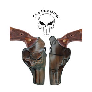 May include: Two brown leather gun holsters with a skull design and the text "The Punisher" above. The holsters are designed to fit a revolver, with wooden handles. The holsters are displayed against a white background.