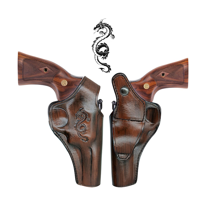 May include: Two brown leather gun holsters with a dragon design, each holding a revolver with a wooden grip. A black dragon illustration is above the holsters. The holsters are made of dark brown leather.