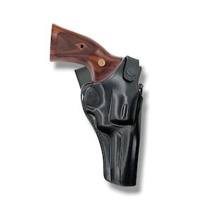 Peut inclure: Un étui en cuir noir avec un revolver. Le revolver a une poignée en bois avec un emblème doré. L'étui est conçu pour maintenir l'arme à feu en toute sécurité, avec une forme moulée et des détails de couture.
