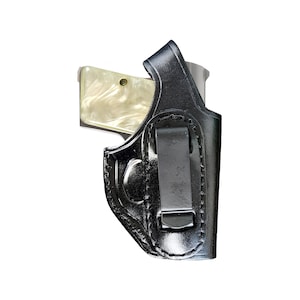 May include: A black leather holster with a clip for carrying a small handgun. The holster has a stitched design and a smooth finish.