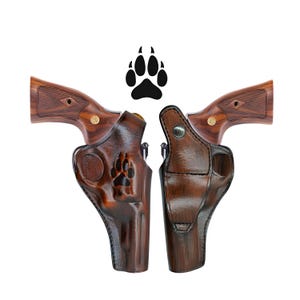 May include: Two brown leather holsters with a dark wood grain finish, each containing a revolver with a polished wooden grip. The holsters feature a stamped paw print design on the front, and a black paw print icon is centered above the two items.