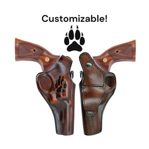May include: Two brown leather holsters for a revolver with a paw print design. The holsters are customizable. The text "Customizable!" is above the holsters.