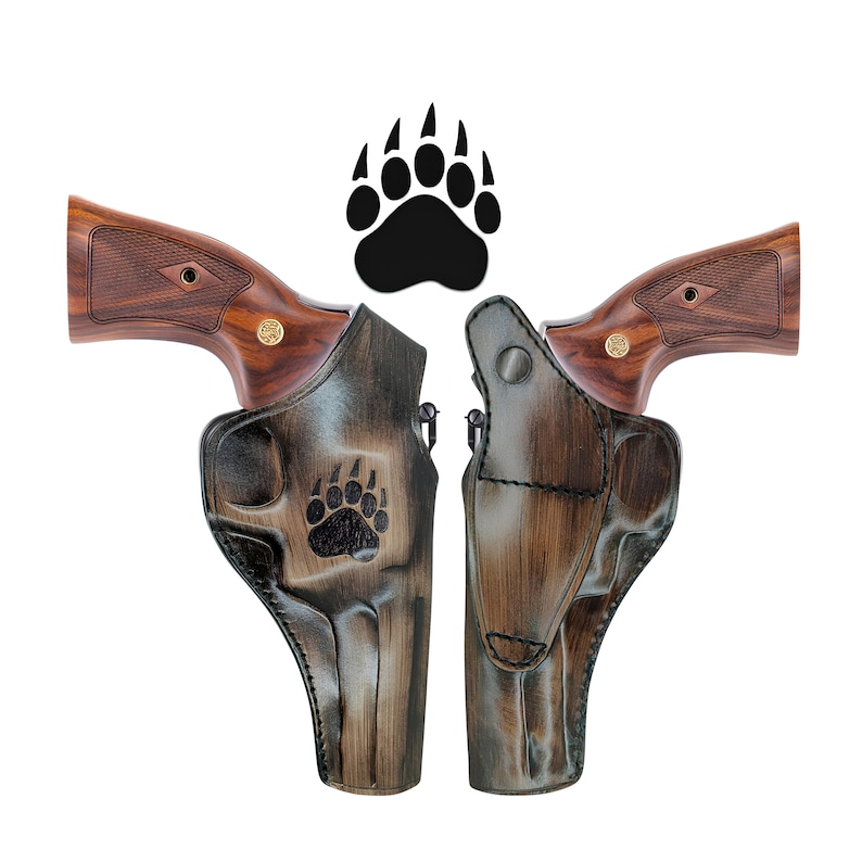 May include: Two brown leather holsters with a bear paw design. The holsters are designed to hold a revolver.