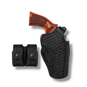 Peut inclure: Un étui en cuir noir avec un motif tissé, contenant un revolver avec une poignée en bois. Une pochette de magazine noire assortie est également présente. Les articles sont sur fond blanc.