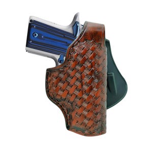 May include: A brown leather holster with a woven basketweave pattern holds a silver and blue handgun. The holster has a dark green backing and is designed to be worn on the hip.