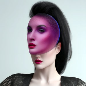 May include: A woman with black hair and a pink and blue geometric mask over her face. She is wearing a black lace top.