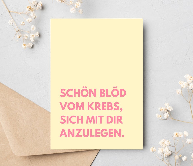 May include: A yellow card with pink text that reads "Sch&ouml;n bl&ouml;d vom Krebs, sich mit dir anzulegen."
