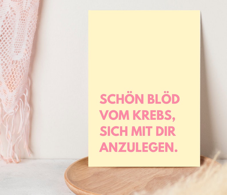 May include: A yellow poster with pink text that reads "Sch&ouml;n bl&ouml;d vom Krebs, sich mit dir anzulegen."