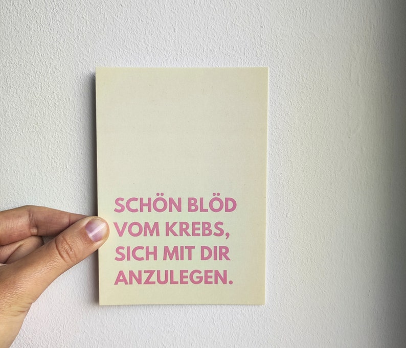 May include: A light yellow card with pink text that reads "Sch&ouml;n bl&ouml;d vom Krebs, sich mit dir anzulegen."