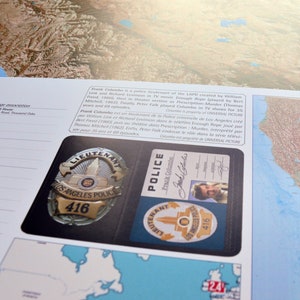 May include: A close-up of a police badge and identification card. The badge is a gold-colored metal badge with the words "Los Angeles Police" and the number "416" on it. The identification card is a blue card with the words "Police" and "Frank Columbo" on it. The card also has a picture of a man in a suit.