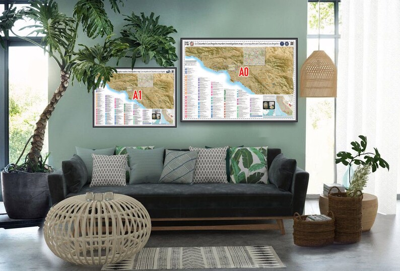 May include: Two framed maps of a coastal region with detailed information and a legend. The maps are hanging on a light green wall above a dark gray sofa with pillows. The sofa is in a living room with a potted plant, a wicker ottoman, and a woven pendant light.